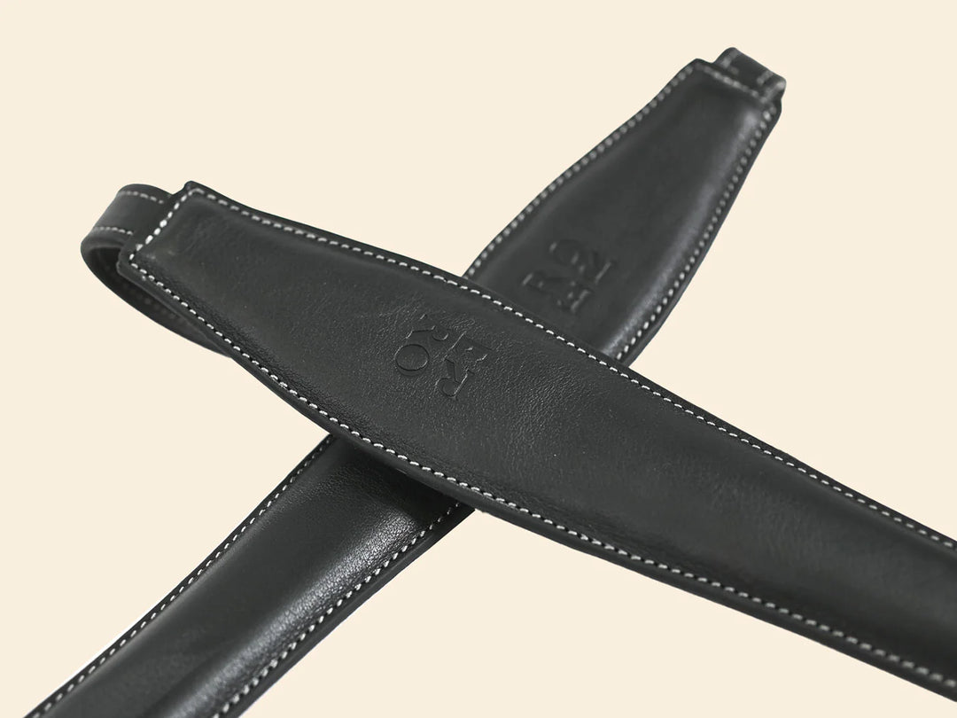 Black leather belt with visible stitching on a beige background