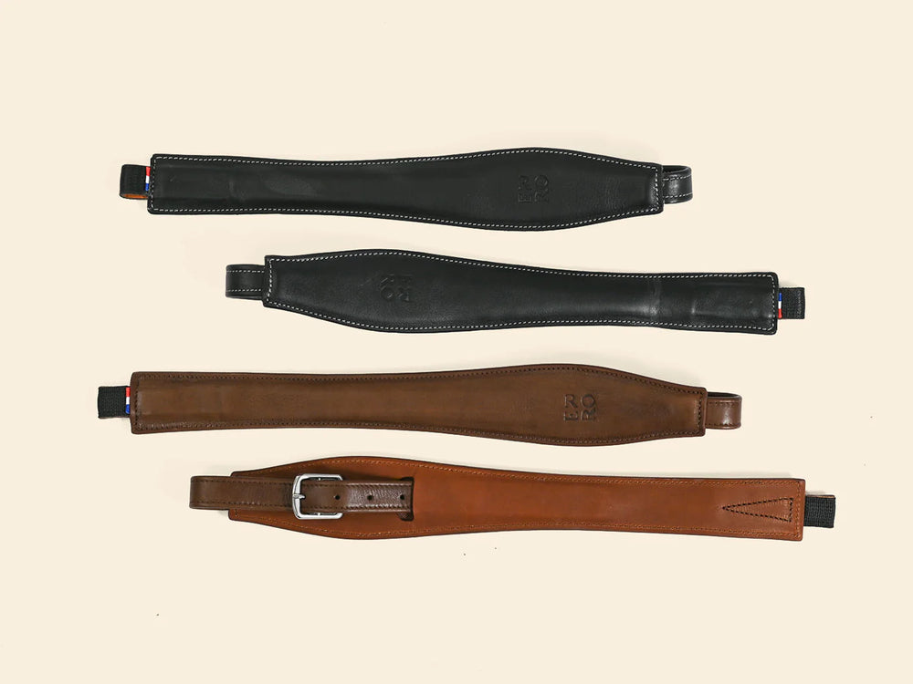 Four leather girth straps in black and brown on a beige background